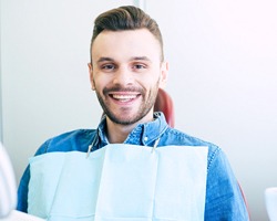 Happy male dental patient in blue shirt smiling after treatment