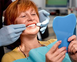 Senior woman in dental chair looking at her smile in the mirror