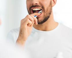 Man in white shirt brushing his teeth