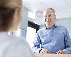 An older man smiling at a dental employee.