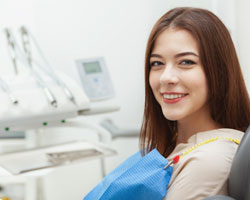 A young woman seated in the dentist’s chair preparing to receive preventive treatment to improve her smile