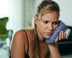 Woman holding ice pack to cheek