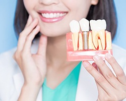 Dentist holding model of dental implants in Highland Park