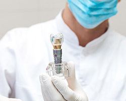 Dentistin holding up an implant model