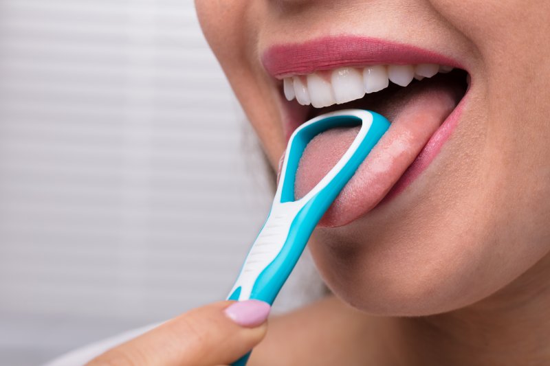 woman scraping her tongue with tool