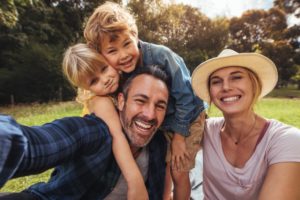 smiling family of four sitting outdoors 