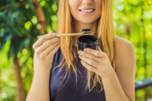 Woman using activated charcoal to brush her teeth. 