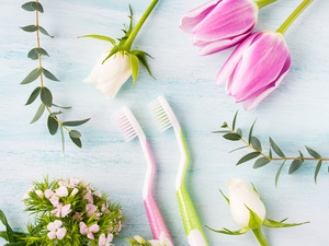 Two toothbrushes lying on table surrounded by spring flowers