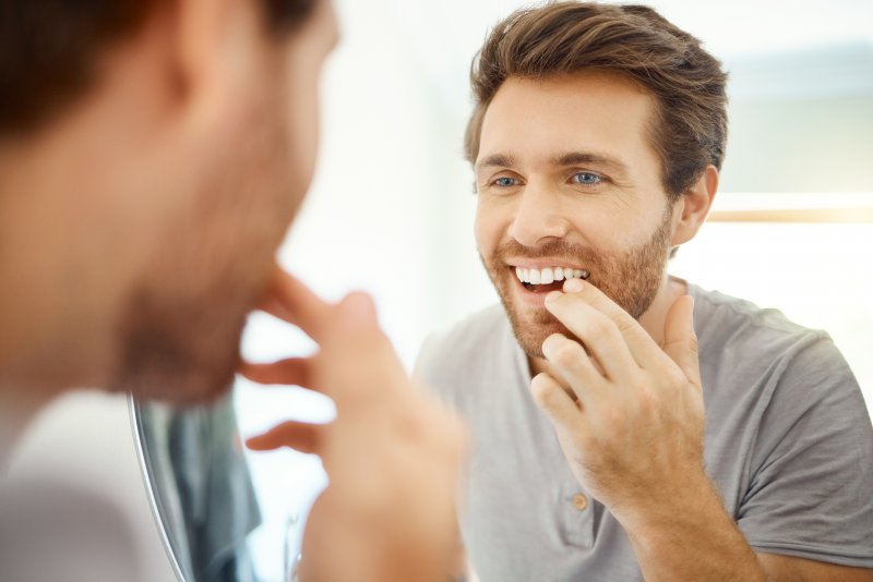 Patient smiling at tooth-colored fillings in mirror